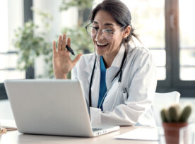 女医生在会诊时用笔记本电脑与同事进行视频通话，挥手交谈。