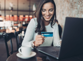 女人在电脑前看着她的信用卡，微笑着